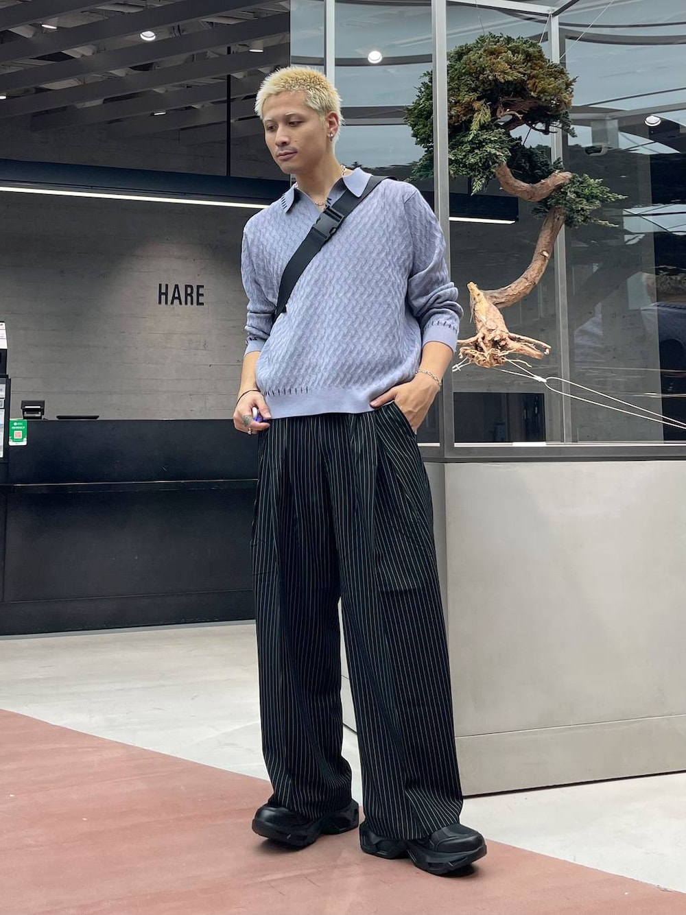 ブラック系のスラックス、ブラック系のメッセンジャーバッグ、パープル系のポロシャツを着用したメンズの秋コーディネートの1枚目の写真