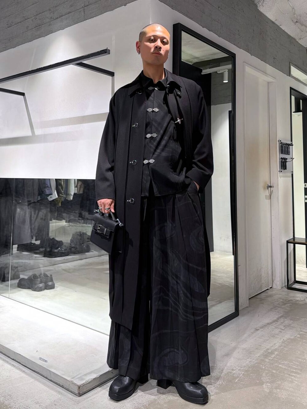 グレー系のその他パンツ、ブラック系のブーツ、ブラック系のハンドバッグを着用したメンズの冬コーディネートの1枚目の写真