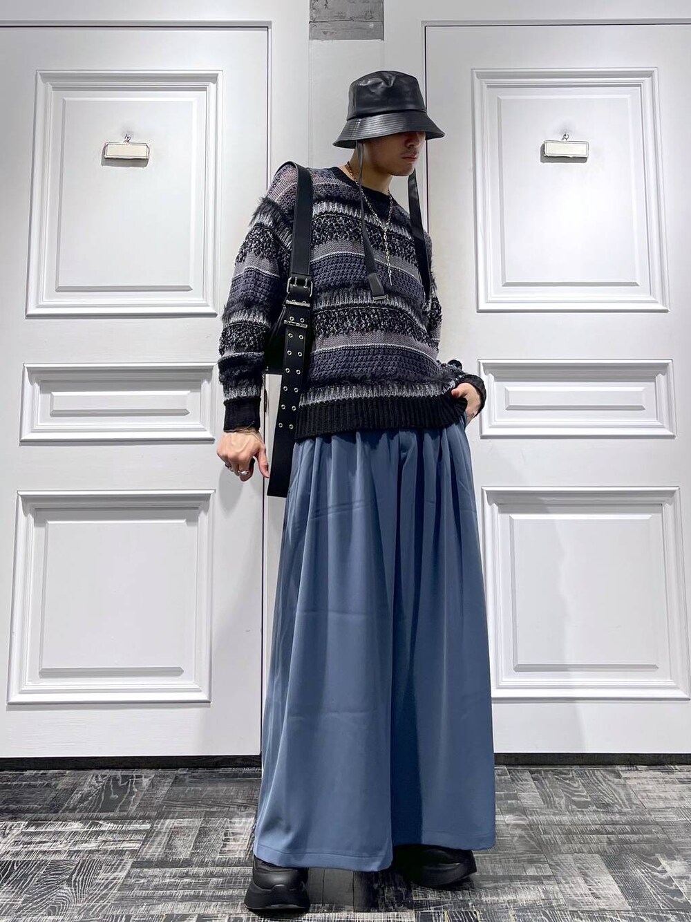 ブラック系のニット/セーター、ブルー系のスラックス、ブラック系のスニーカーを着用したメンズの春コーディネートの1枚目の写真