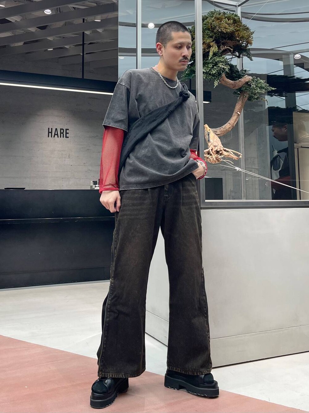 レッド系のTシャツ/カットソー、ブラック系のショルダーバッグ、オレンジ系のデニムパンツを着用したメンズの春コーディネートの1枚目の写真