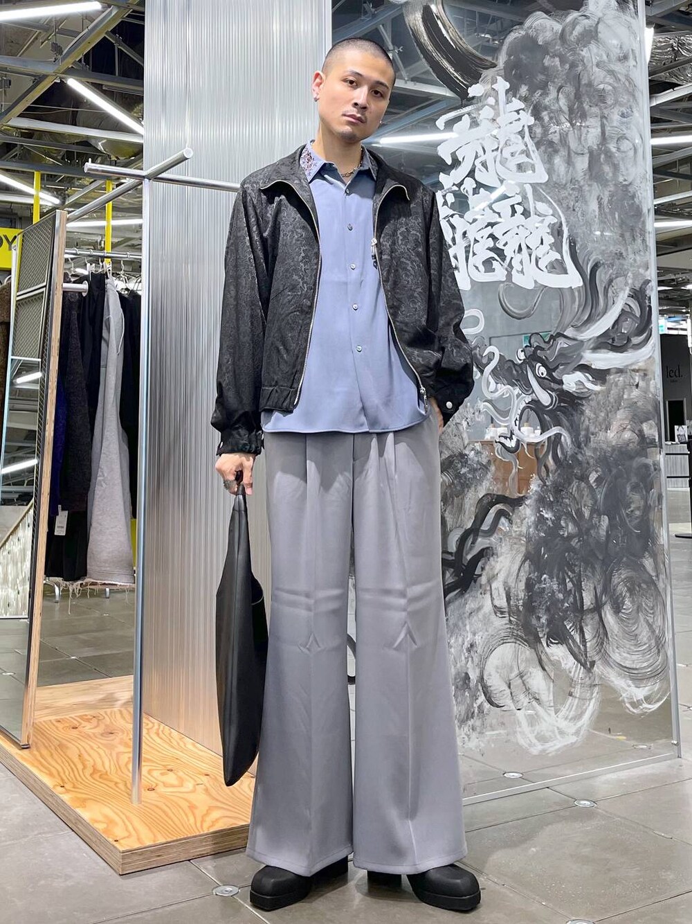 グレー系のスラックス、ブルー系のシャツ/ブラウス、ブラック系のトートバッグを着用したメンズの秋コーディネートの1枚目の写真