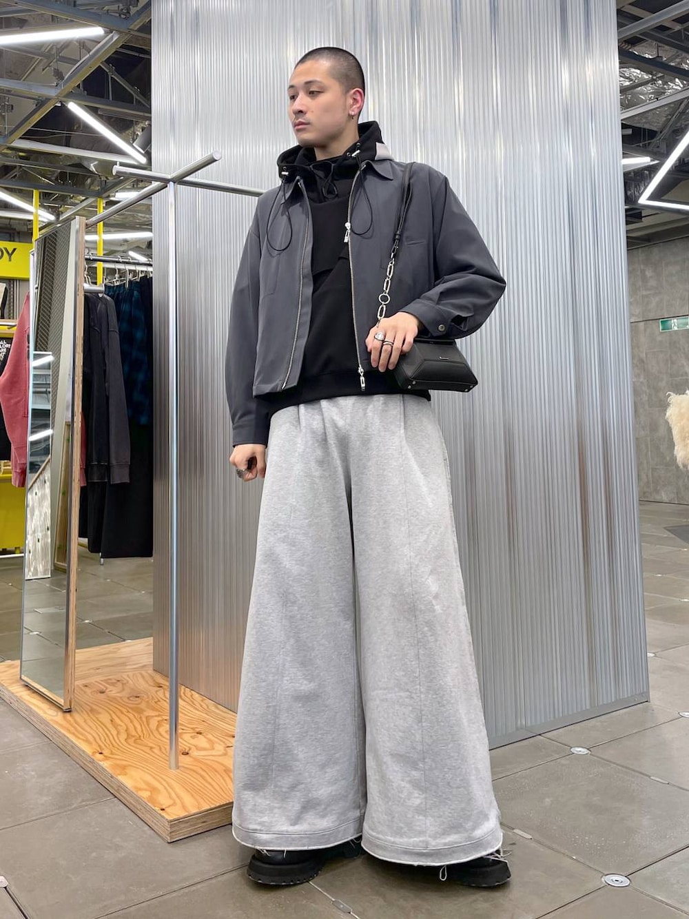 グレー系のスウェットパンツ、ブラック系のショルダーバッグ、グレー系のブルゾンを着用したメンズの春コーディネートの1枚目の写真