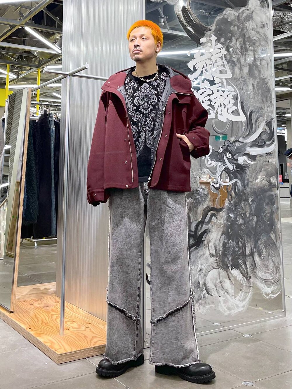 グレー系のデニムパンツ、レッド系のブルゾン、ブラック系のニット/セーターを着用したメンズの秋コーディネートの1枚目の写真