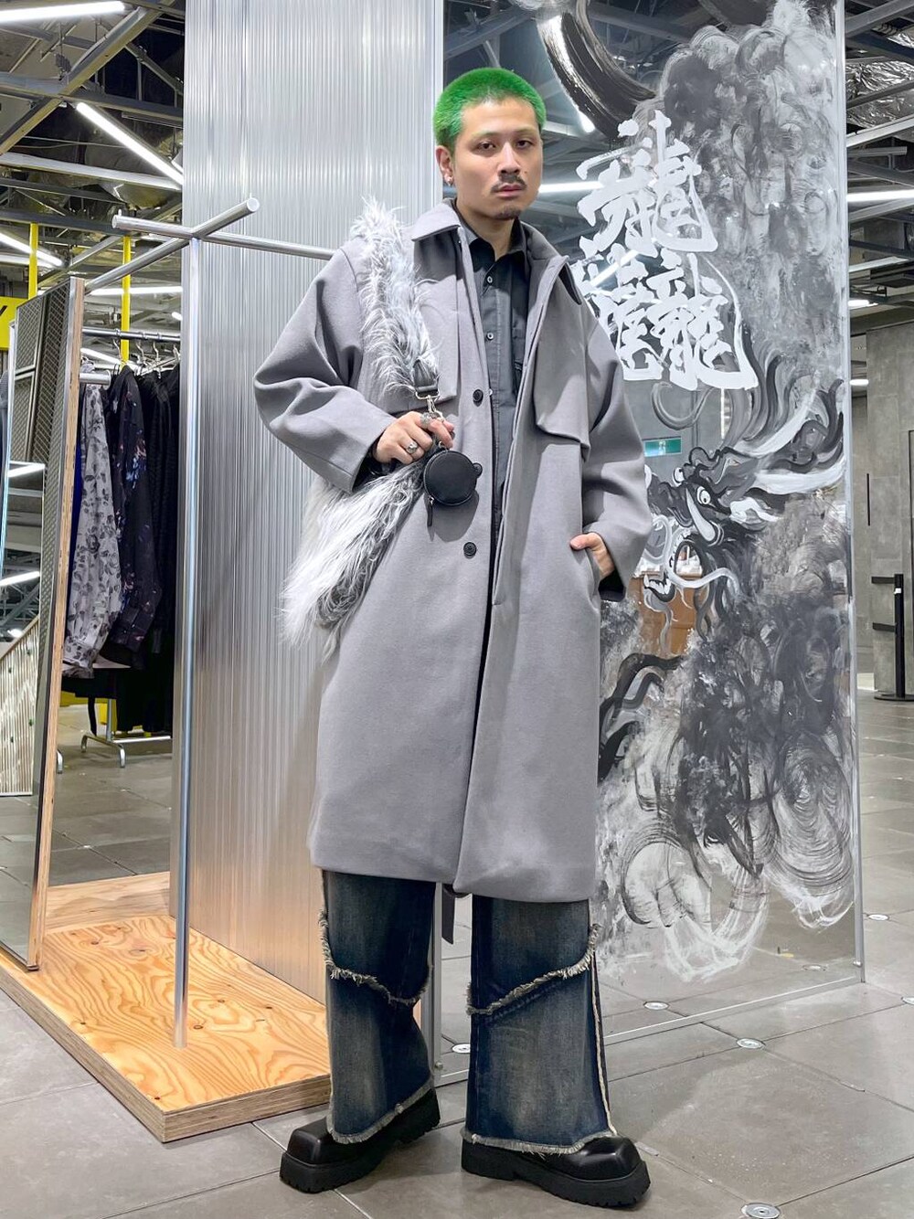 ブルー系のデニムパンツ、グレー系のステンカラーコート、グレー系のショルダーバッグを着用したメンズの秋コーディネートの1枚目の写真