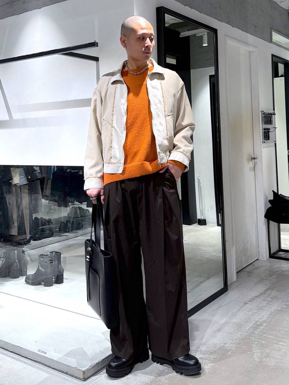 ブラック系のドレスシューズ、ブラック系のトートバッグ、オレンジ系のニット/セーターを着用したメンズの冬コーディネートの1枚目の写真