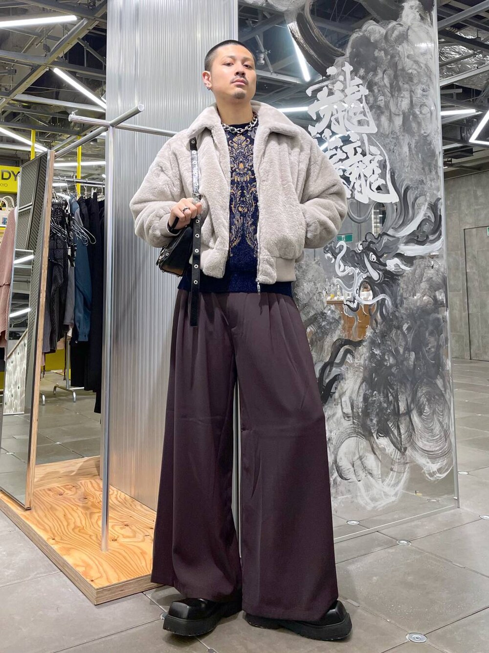 ブルー系のニット/セーター、ブラック系のショルダーバッグ、レッド系のスラックスを着用したメンズの冬コーディネートの1枚目の写真