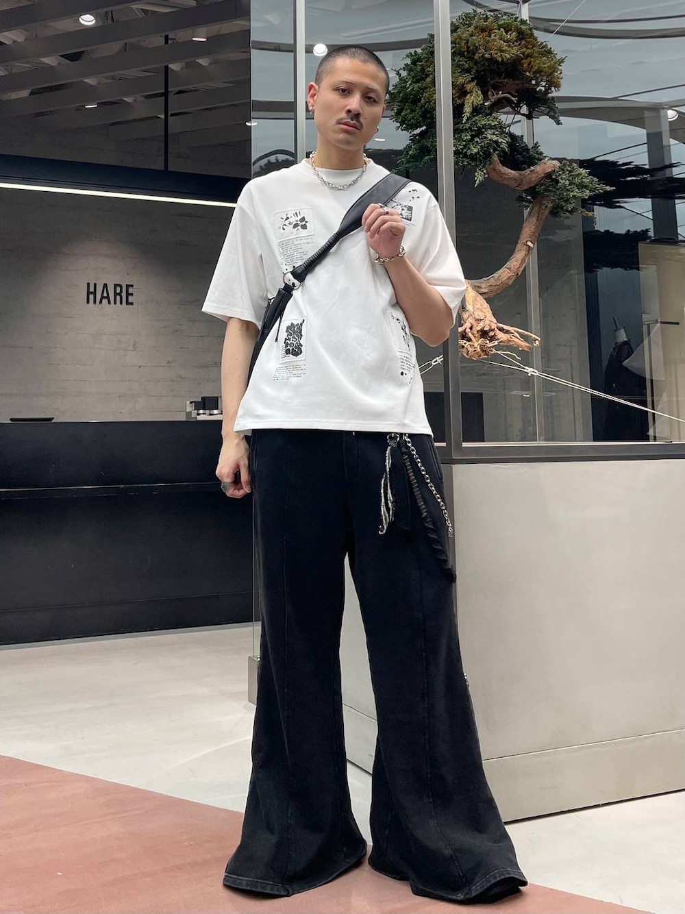 ブラック系のスウェットパンツ、ホワイト系のTシャツ/カットソー、ブラック系のショルダーバッグを着用したメンズの春コーディネートの1枚目の写真