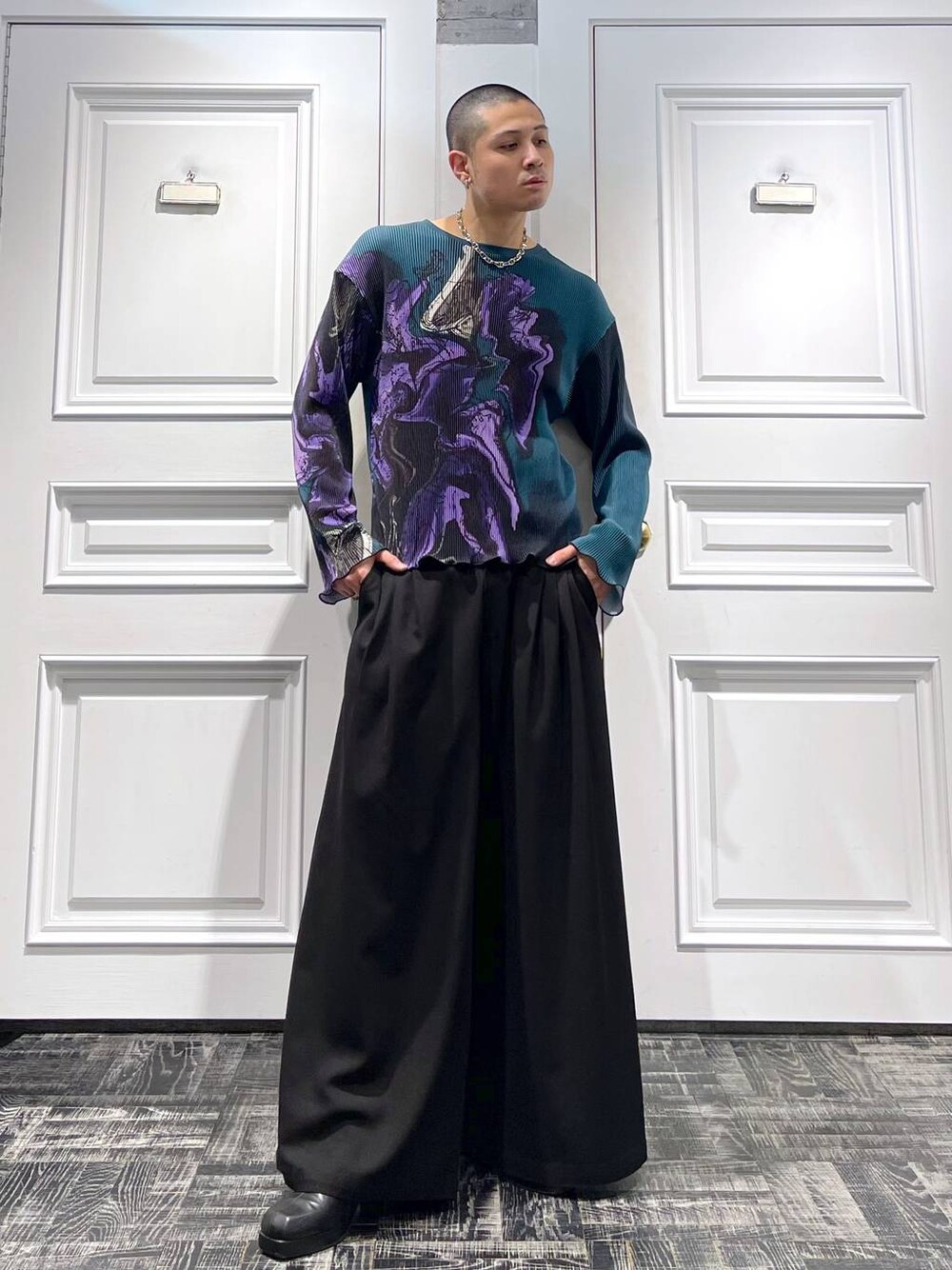 グリーン系のTシャツ/カットソー、ブラック系のスラックス、シルバー系のネックレスを着用したメンズの春コーディネートの1枚目の写真
