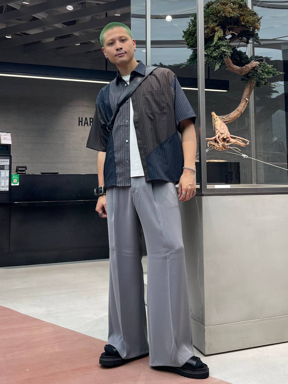 グレー系のスラックス、ブラック系のショルダーバッグ、ブラック系のサンダルを着用したメンズの夏コーディネートの1枚目の写真