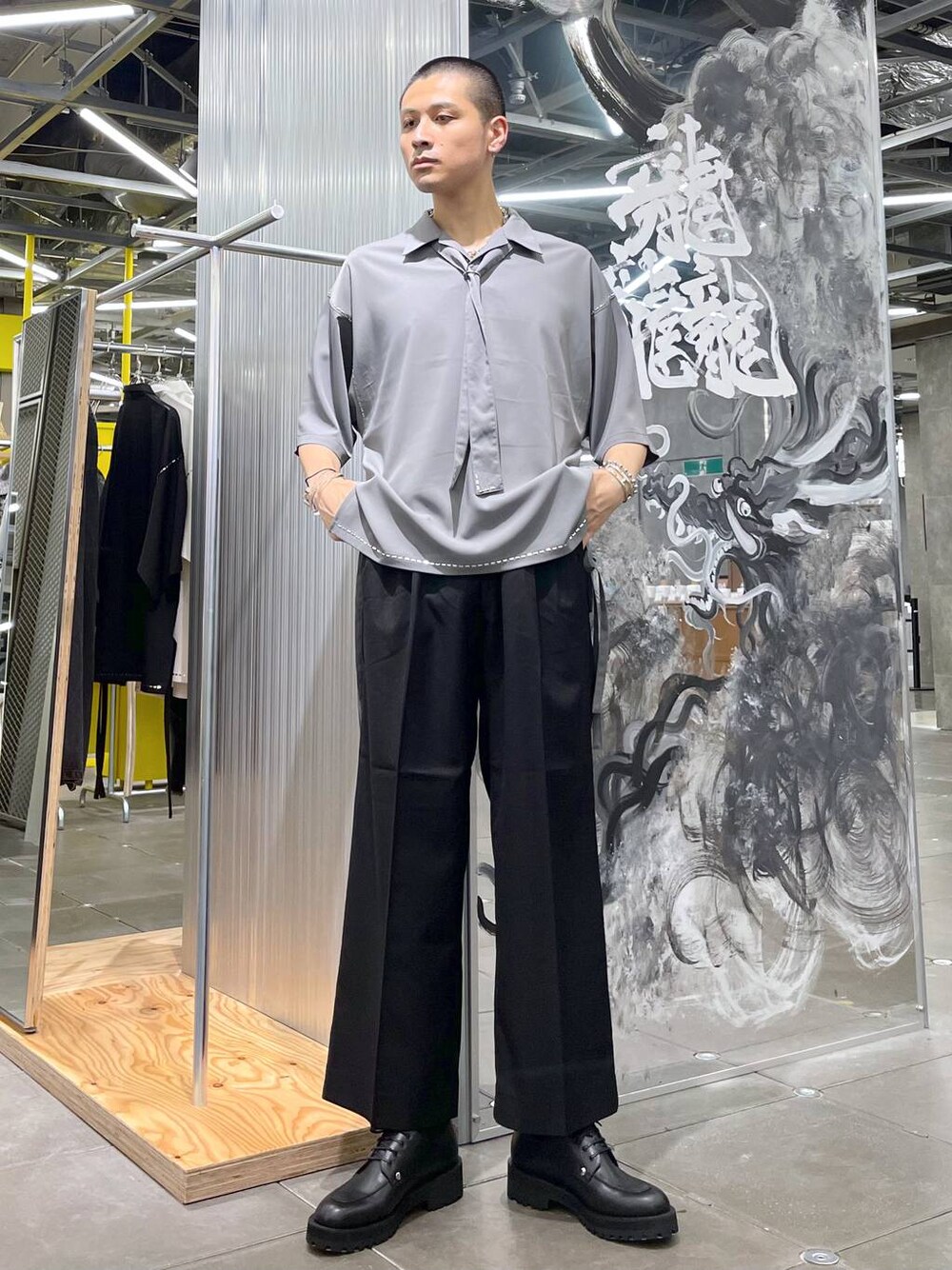 グレー系のシャツ/ブラウス、ブラック系のスラックス、シルバー系のバングル/リストバンドを着用したメンズの夏コーディネートの1枚目の写真