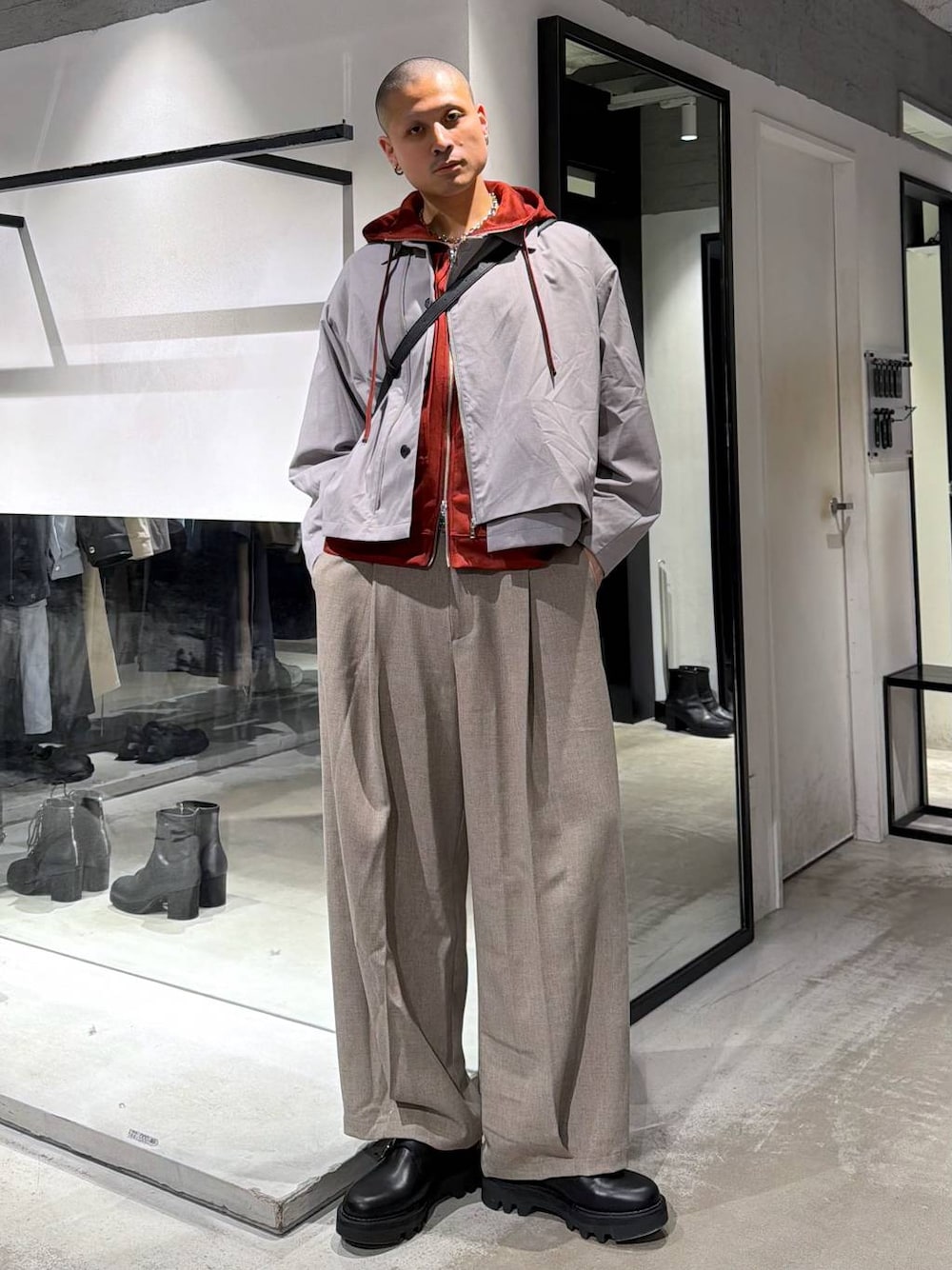 オレンジ系のパーカー、ブラック系のドレスシューズ、ブラック系のショルダーバッグを着用したメンズの春コーディネートの1枚目の写真