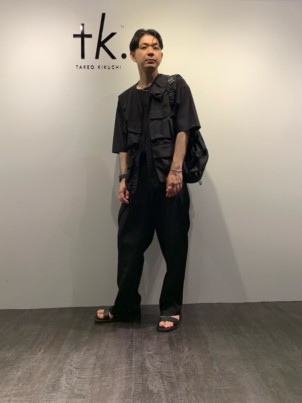 ブラック系のサンダル、ブラック系のスラックス、ブラック系のTシャツ/カットソーを着用したメンズの夏コーディネートの1枚目の写真