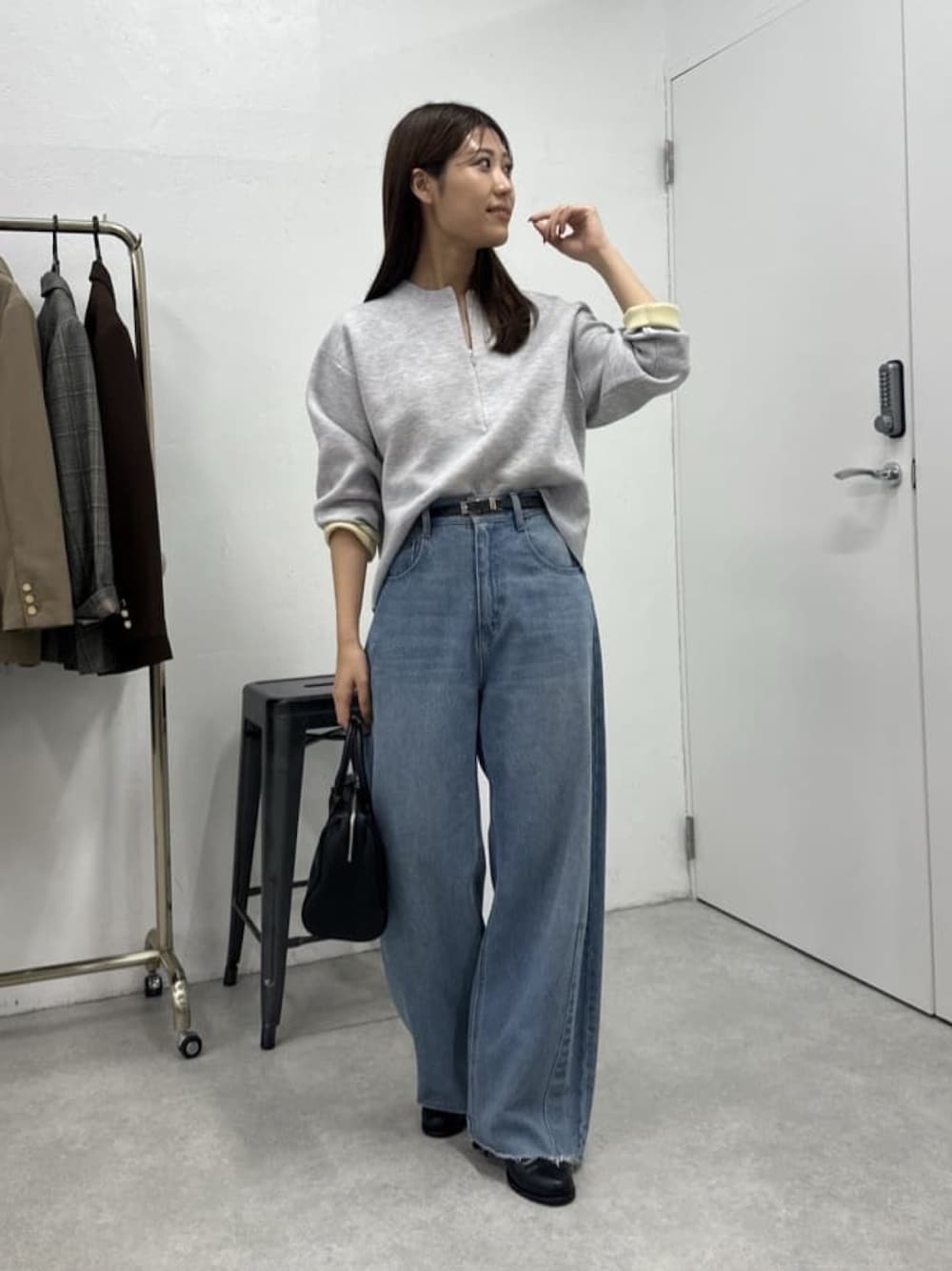 ブルー系のデニムパンツ、グレー系のニット/セーター、ブラック系のボストンバッグを着用したレディースの冬コーディネートの1枚目の写真