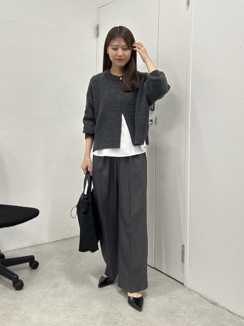 グレー系のニット/セーター、ホワイト系のシャツ/ブラウス、グレー系のスラックスを着用したレディースの冬コーディネートの1枚目の写真