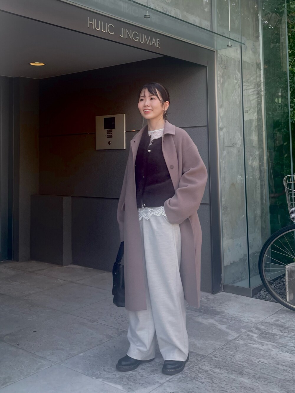 グリーン系のステンカラーコート、ブラウン系のカーディガン/ボレロ、ホワイト系のシャツ/ブラウスを着用したレディースの秋コーディネートの1枚目の写真