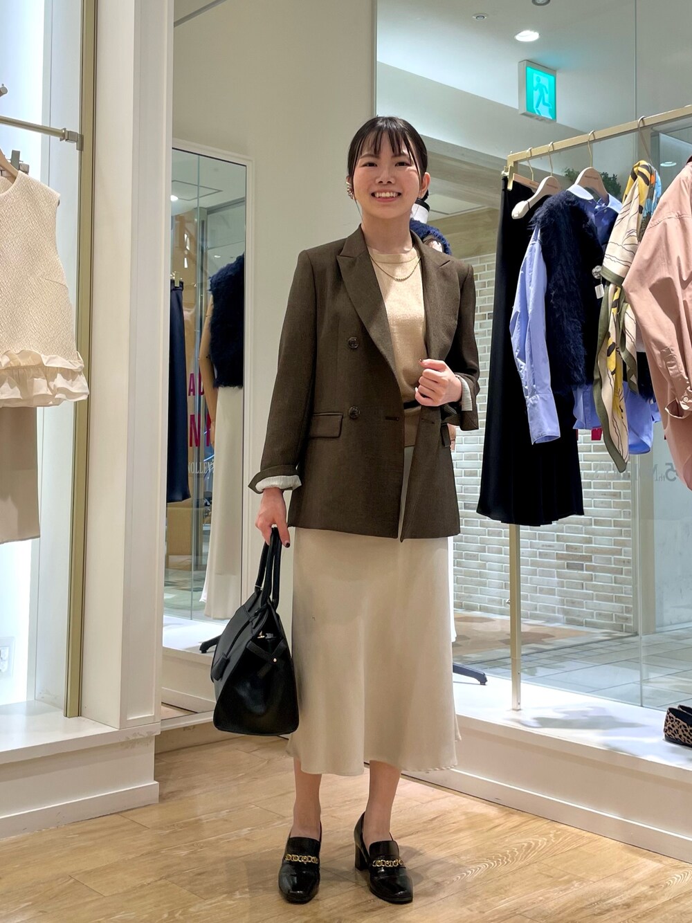 ブラウン系のテーラードジャケット、イエロー系のニット/セーター、ブラック系のショルダーバッグを着用したレディースの秋コーディネートの1枚目の写真