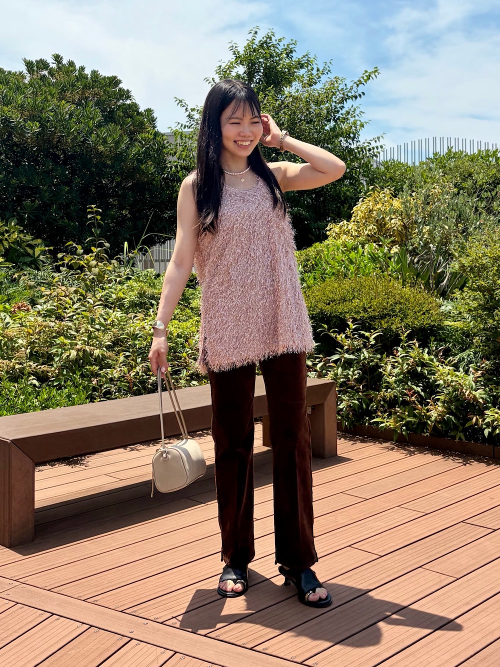 ピンク系のベスト、ブラウン系のその他パンツ、ベージュ系のショルダーバッグを着用したレディースの夏コーディネートの1枚目の写真