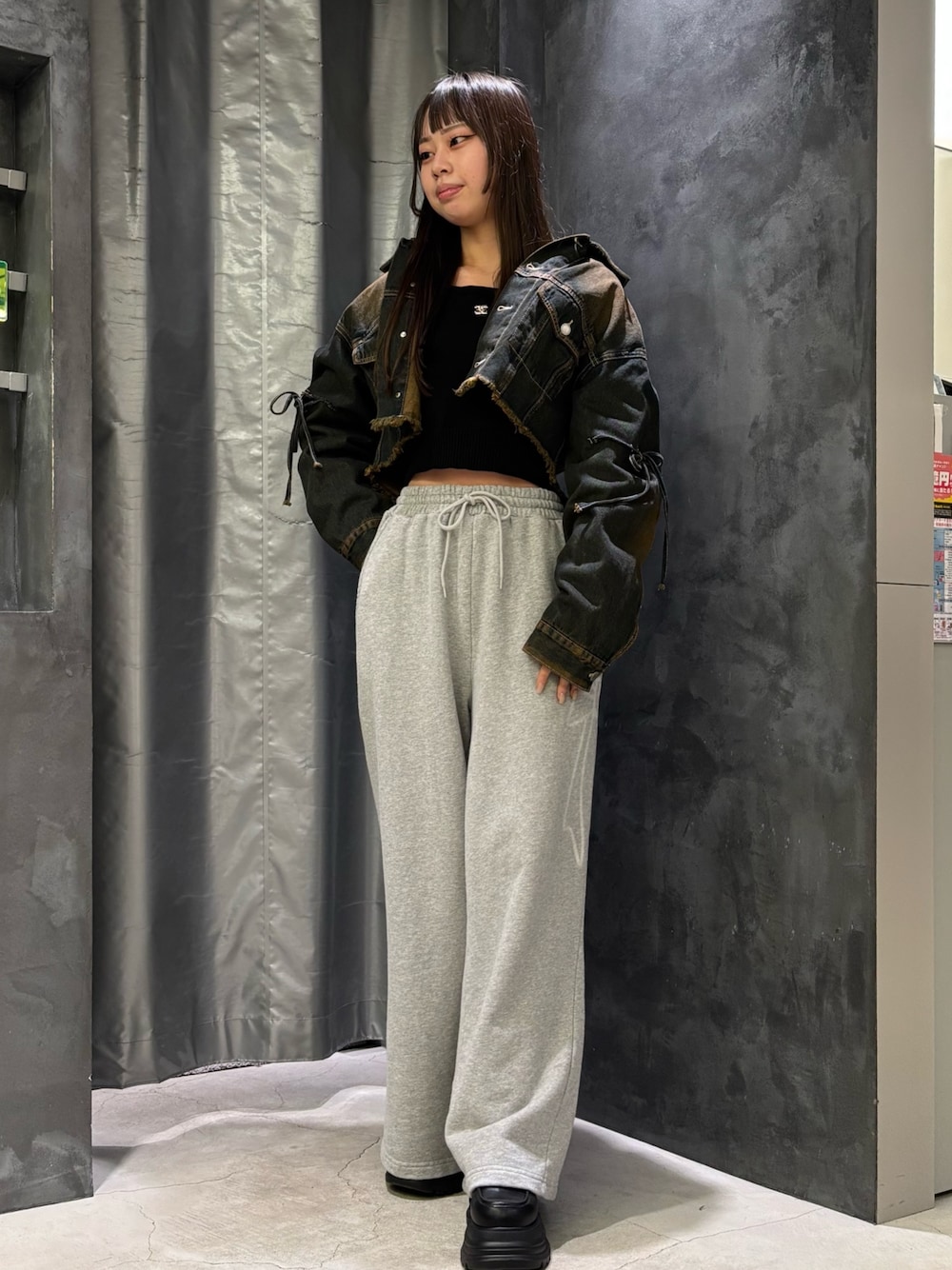 ブルー系のデニムジャケット、ブラック系のニット/セーター、グレー系のスウェットパンツを着用したレディースの冬コーディネートの1枚目の写真