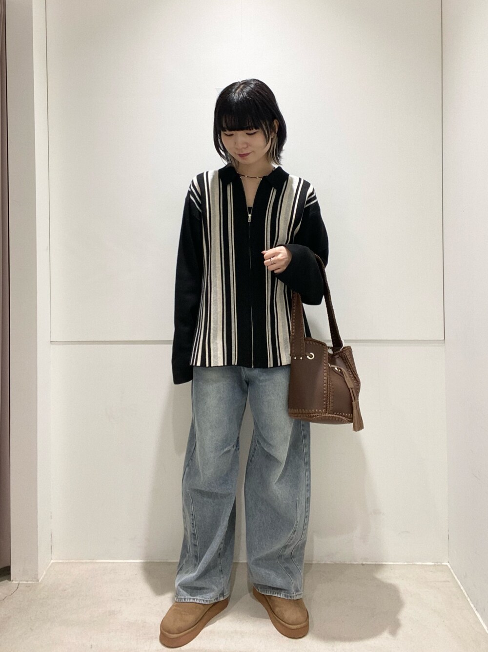 ブラック系のニット/セーター、ブルー系のデニムパンツ、ブラウン系のショルダーバッグを着用したレディースの秋コーディネートの1枚目の写真