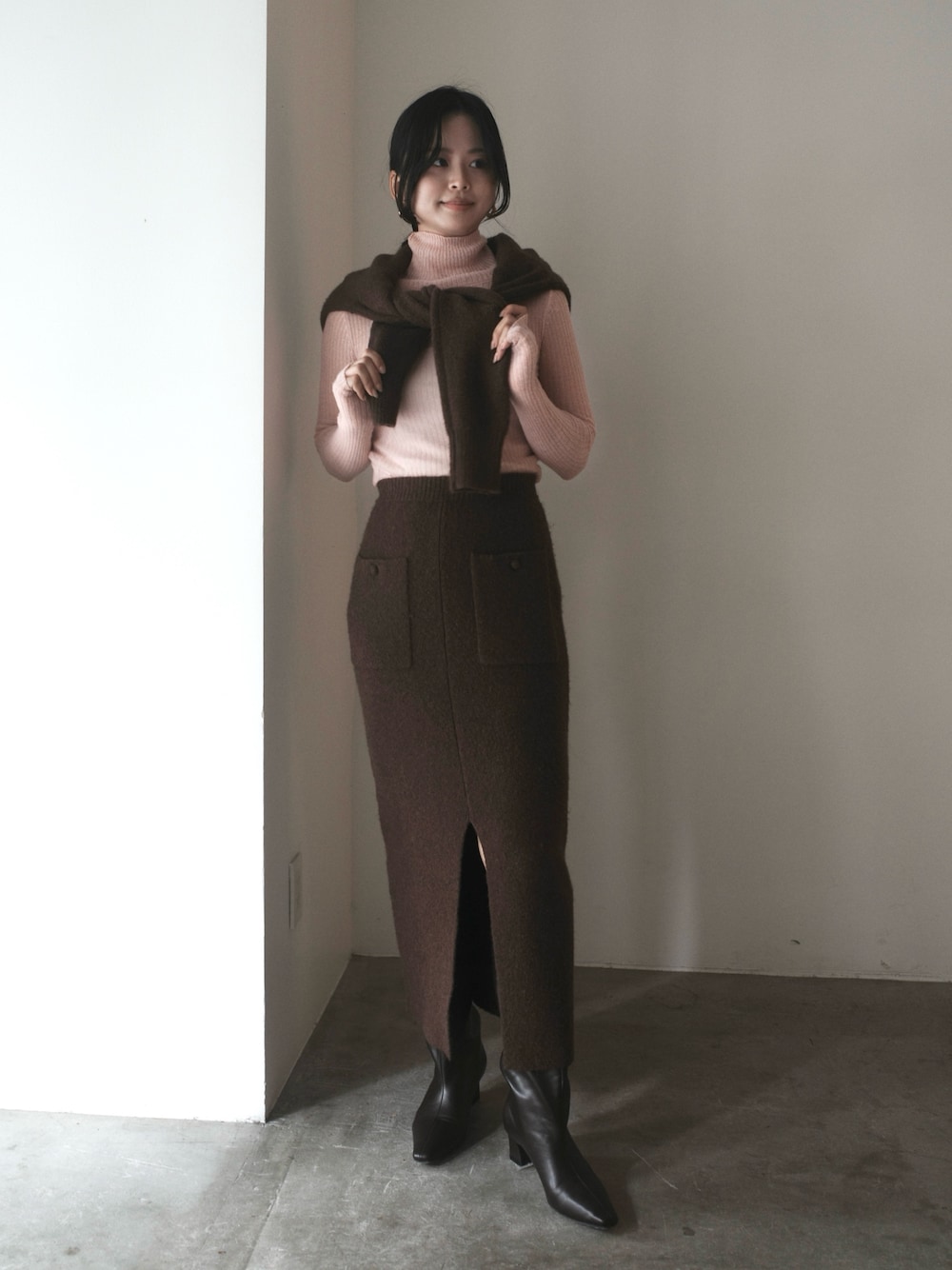 ピンク系のニット/セーター、ブラウン系のワンピース、ブラウン系のブーツを着用したレディースの秋コーディネートの1枚目の写真