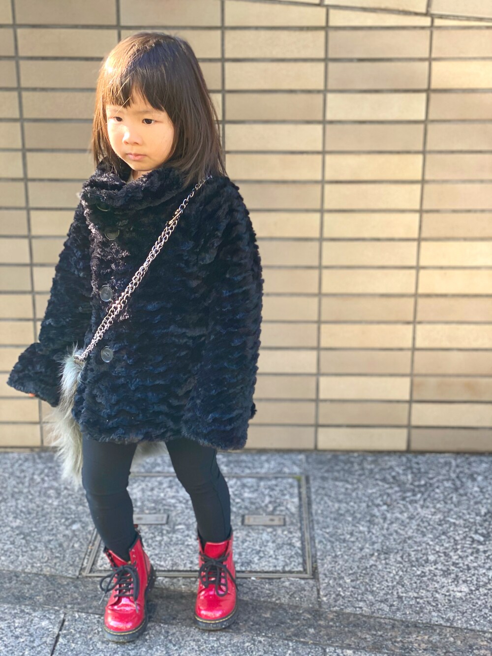 「キッズファッション、patagonia、Dr.Martens、ブーツ、コート、黒コーデ、赤、シンプルコーデ、ショルダーバッグ、カジュアルコーデ、ファーバッグ、ワントーンコーデ」｜「patagoniaのアイテム（ジャケット/アウター、ブラック系）」を使った、Rin&Rayさん（キッズ・100cm）の冬コーディネートの1枚目の写真