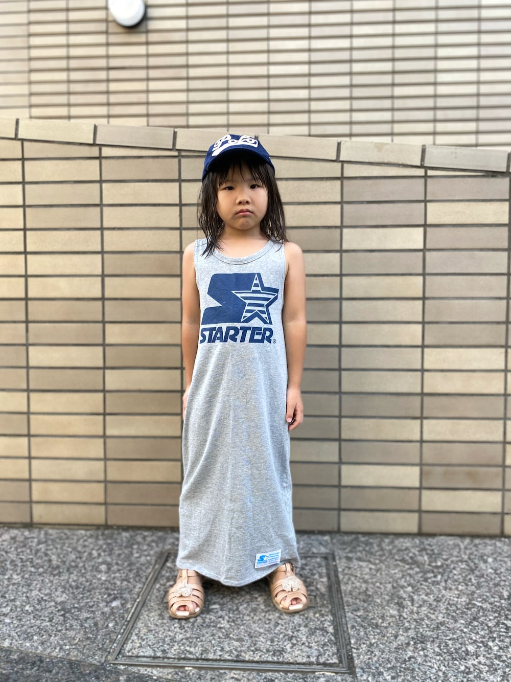 グレー系のワンピース、ブルー系のキャップを着用したキッズの夏コーディネートの1枚目の写真