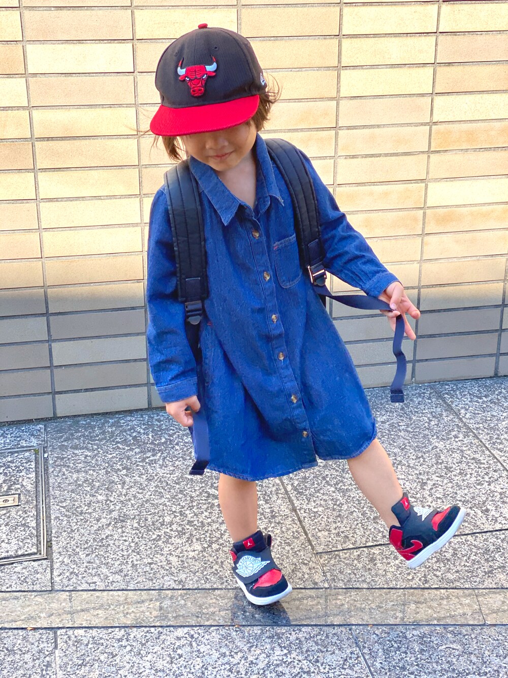 ブルー系のワンピース、ベージュ系のトップス、ブラック系のスニーカーを着用したキッズの秋コーディネートの1枚目の写真