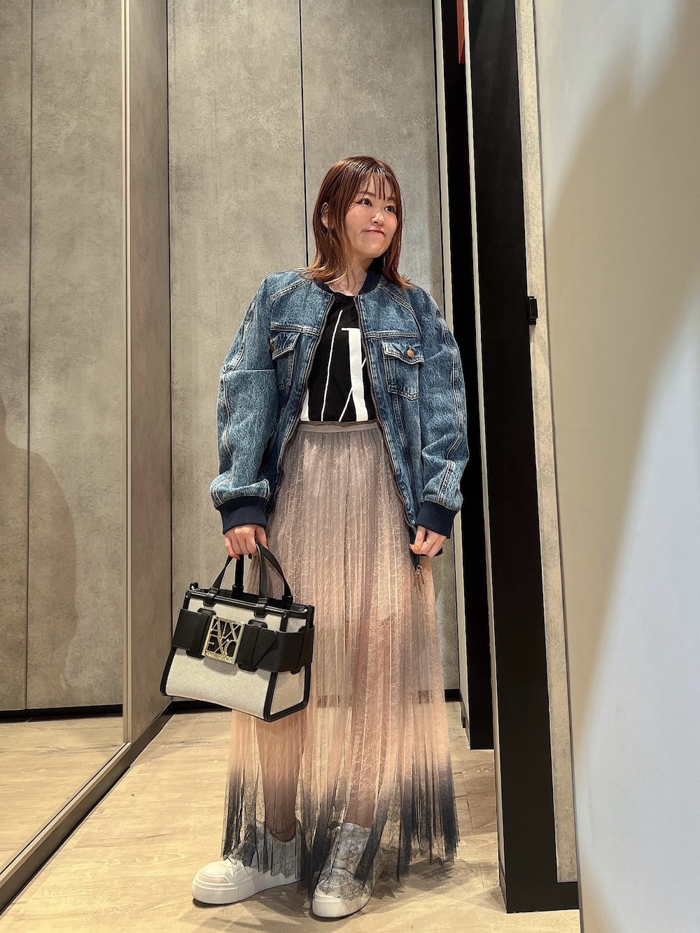 ブラック系のハンドバッグ、ホワイト系のスニーカー、ブルー系のデニムジャケットを着用したレディースの夏コーディネートの1枚目の写真