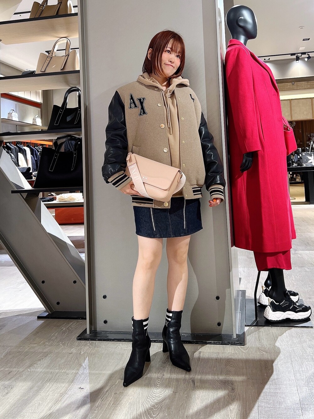 ブルー系のデニムスカート、ブラック系のブーツ、ベージュ系のパーカーを着用したレディースの冬コーディネートの1枚目の写真