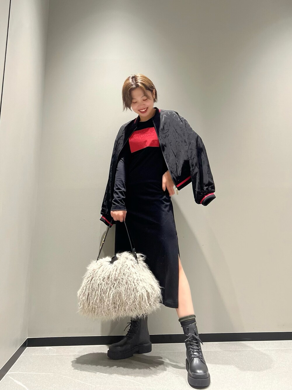 ブラック系のブルゾン、ブラック系のワンピース、ベージュ系のハンドバッグを着用したレディースの秋コーディネートの1枚目の写真