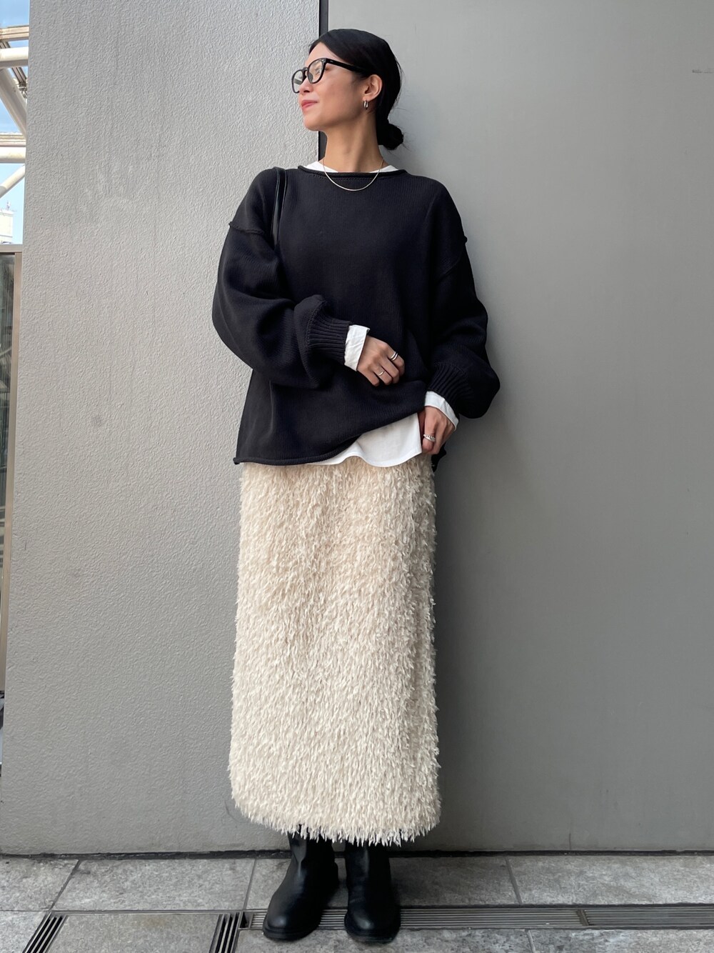 グレー系のニット/セーター、ホワイト系のTシャツ/カットソー、ホワイト系のスカートを着用したレディースの秋コーディネートの1枚目の写真