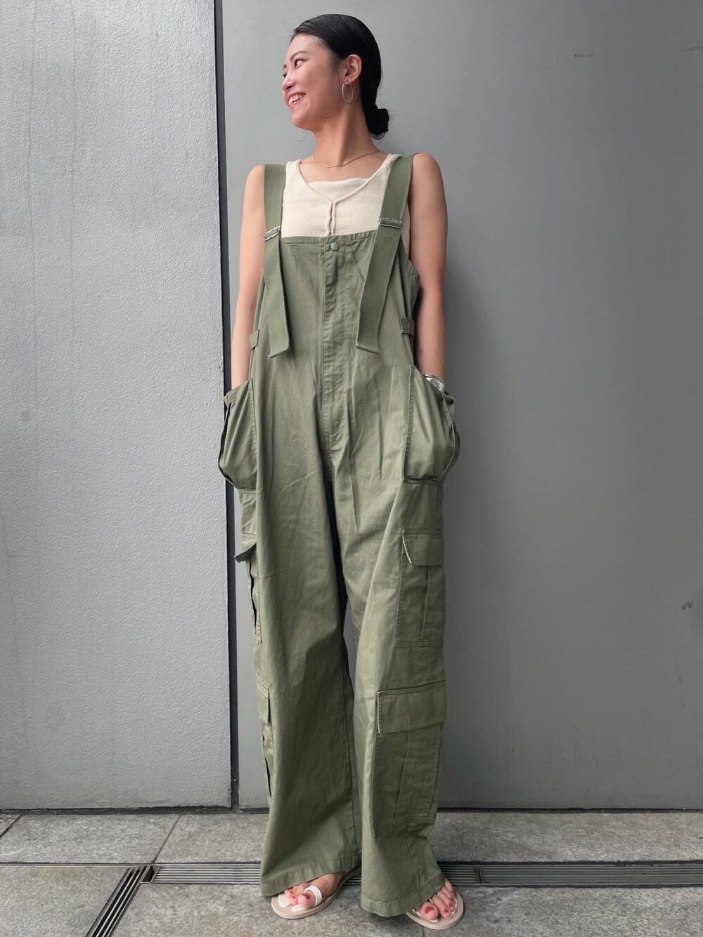 グリーン系のサロペット/オーバーオール、ブラウン系のベスト、ホワイト系のキャミソールを着用したレディースの夏コーディネートの1枚目の写真