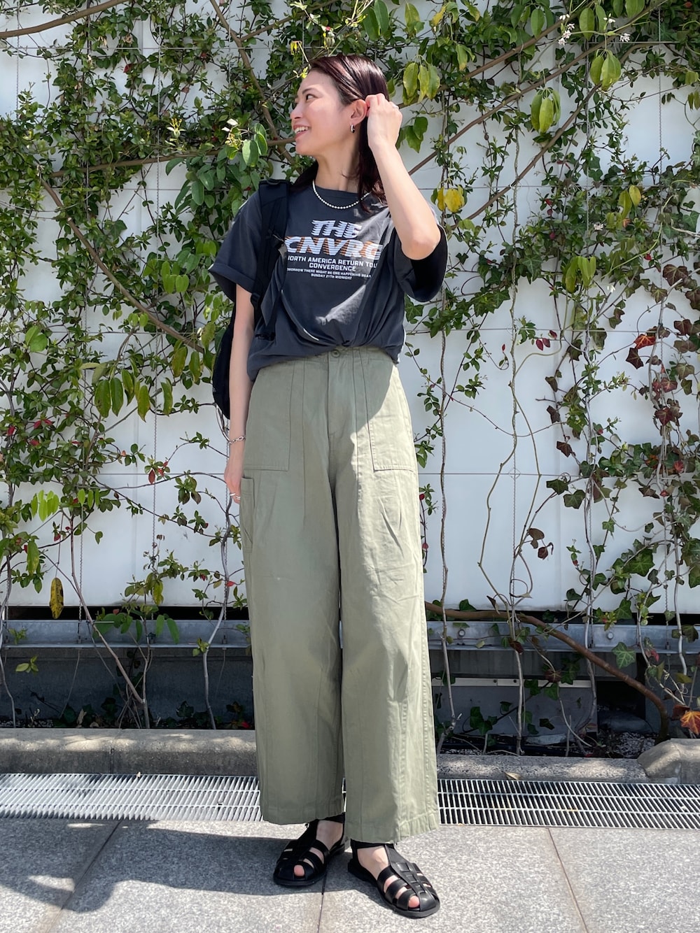 グレー系のTシャツ/カットソー、グリーン系のその他パンツ、ブラック系のサンダルを着用したレディースの春コーディネートの1枚目の写真