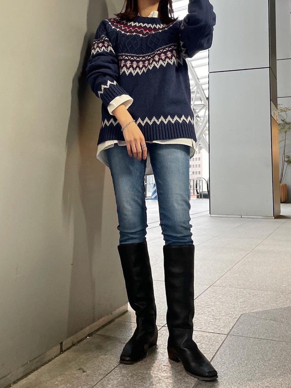 ブルー系のニット/セーター、ホワイト系のシャツ/ブラウス、ブルー系のデニムパンツを着用したレディースの秋コーディネートの1枚目の写真