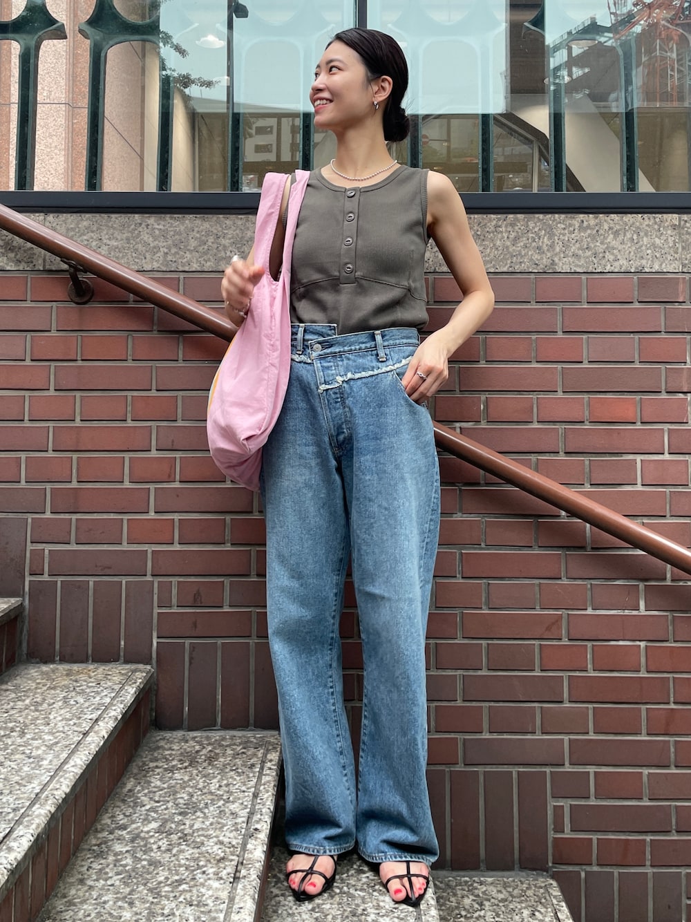 ピンク系のトートバッグ、ブルー系のデニムパンツ、グレー系のタンクトップを着用したレディースの夏コーディネートの1枚目の写真