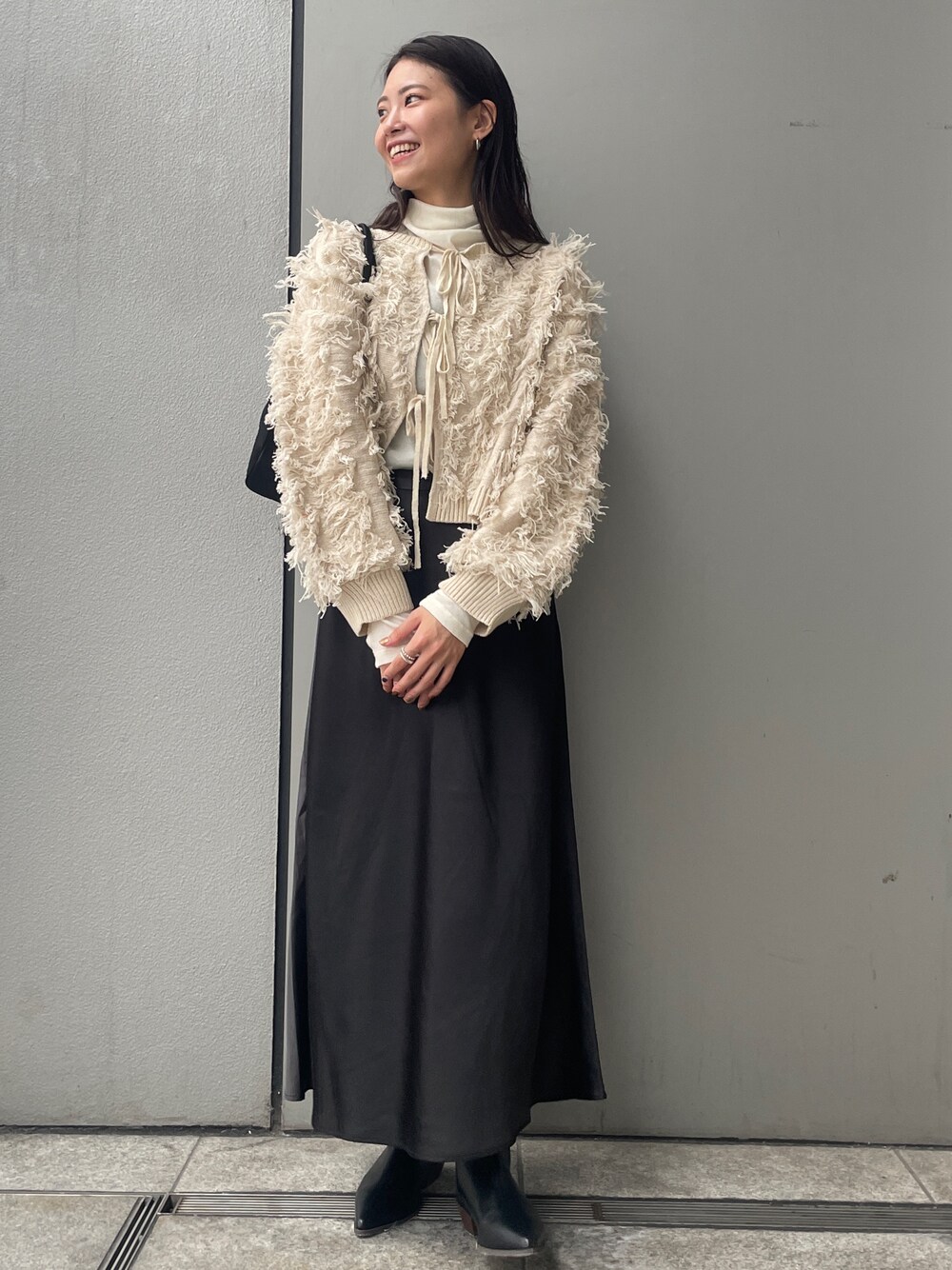 ホワイト系のニット/セーター、ブラック系のスカート、ブラック系のブーツを着用したレディースの秋コーディネートの1枚目の写真