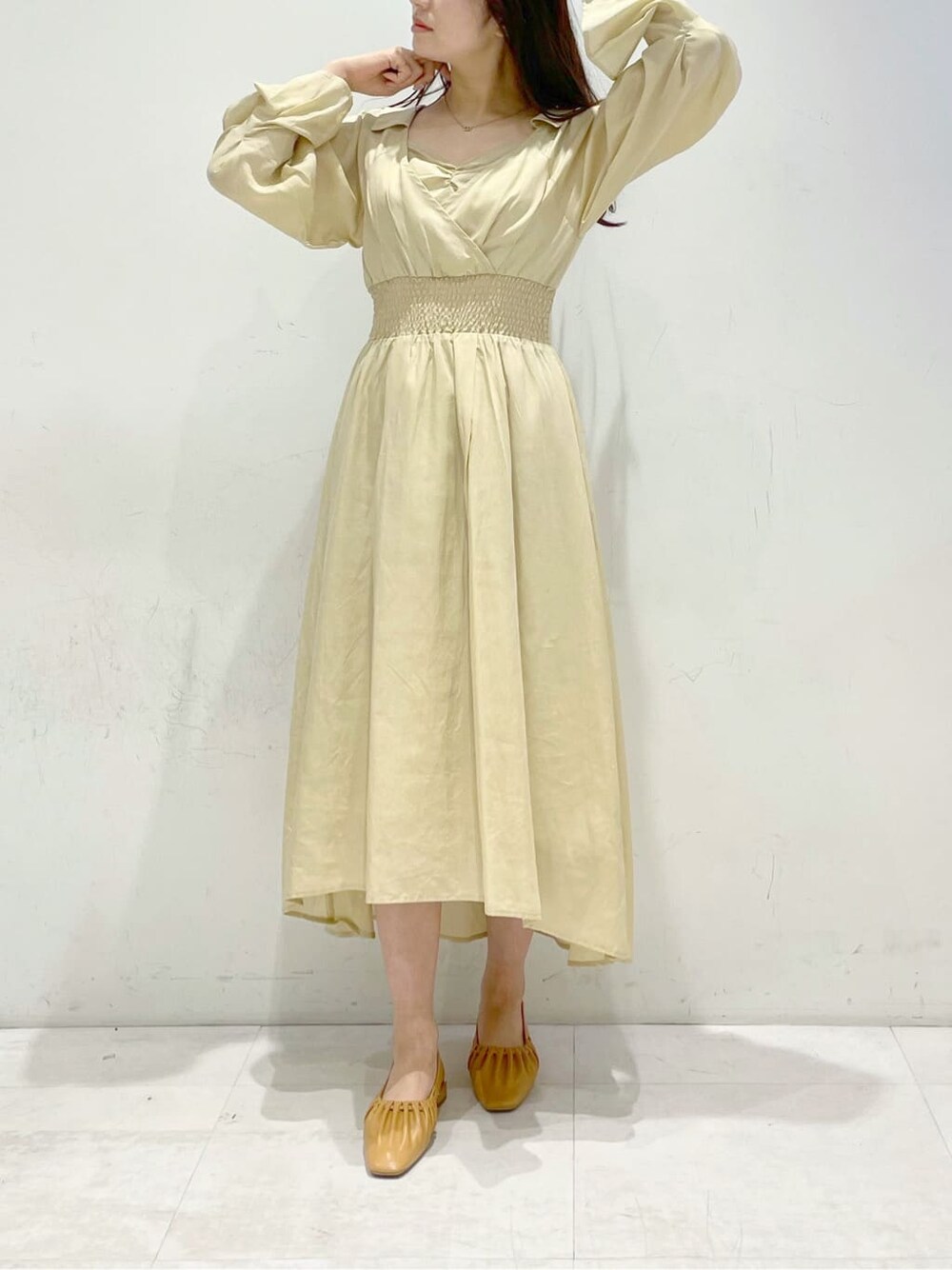 イエロー系のワンピース、ブラウン系のパンプスを着用したレディースの冬コーディネートの1枚目の写真