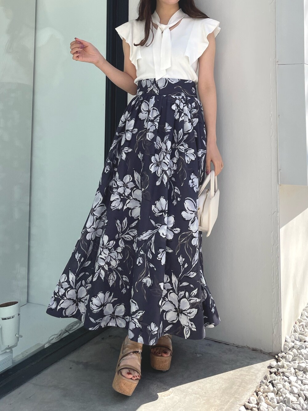 ホワイト系のニット/セーター、パープル系のスカート、ブラック系のハンドバッグを着用したレディースの春コーディネートの1枚目の写真