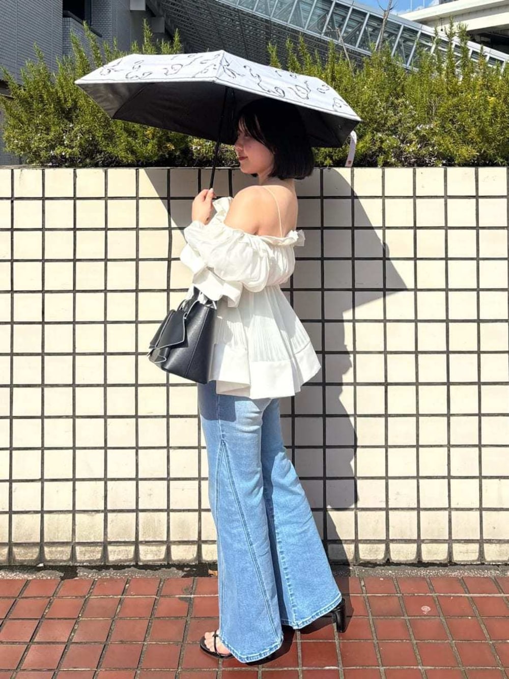 ブルー系のデニムパンツ、ホワイト系のその他トップス、ブラック系のハンドバッグを着用したレディースの春コーディネートの1枚目の写真
