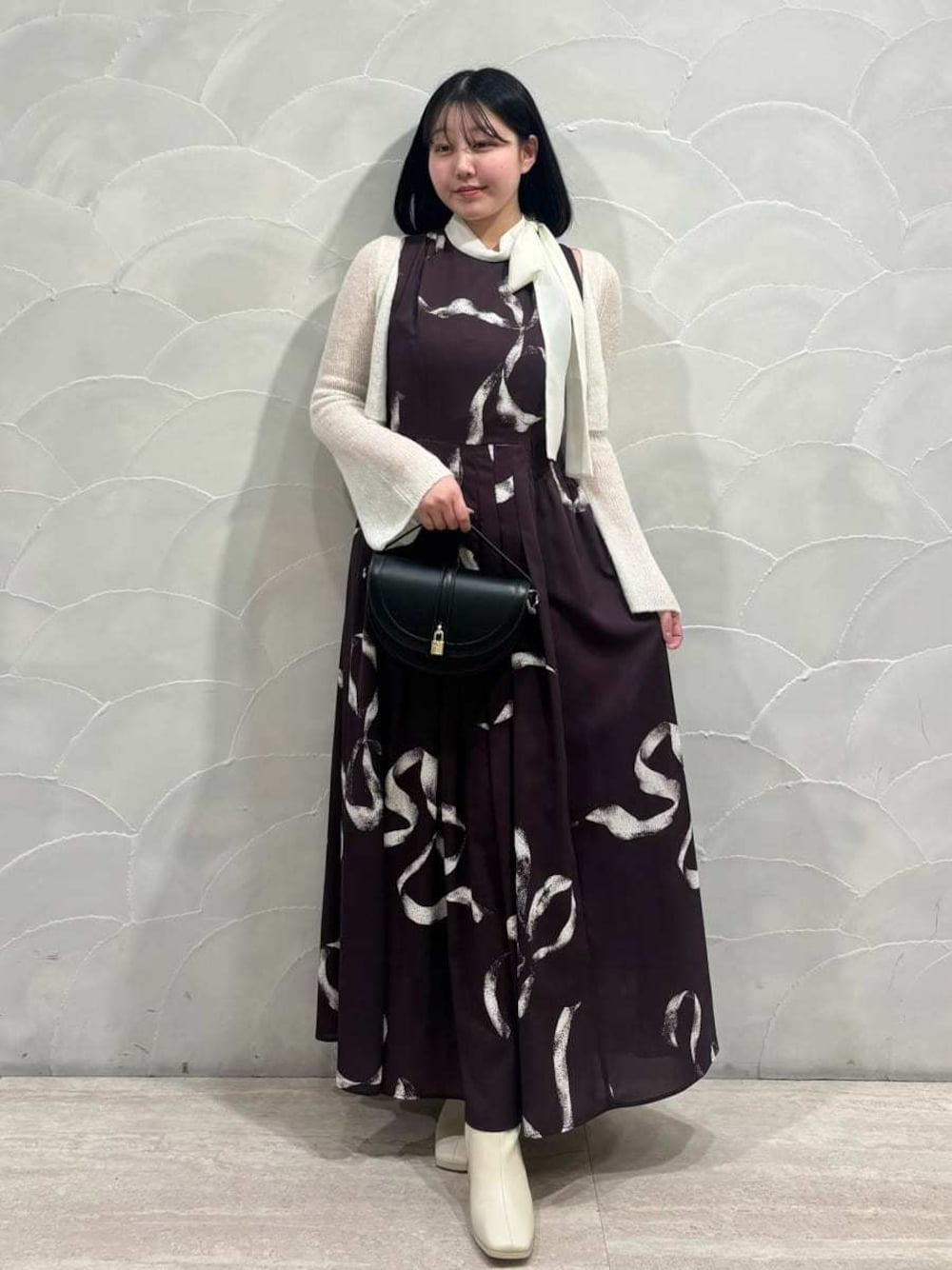 ブラック系のハンドバッグ、ブラウン系のワンピースを着用したレディースの冬コーディネートの1枚目の写真