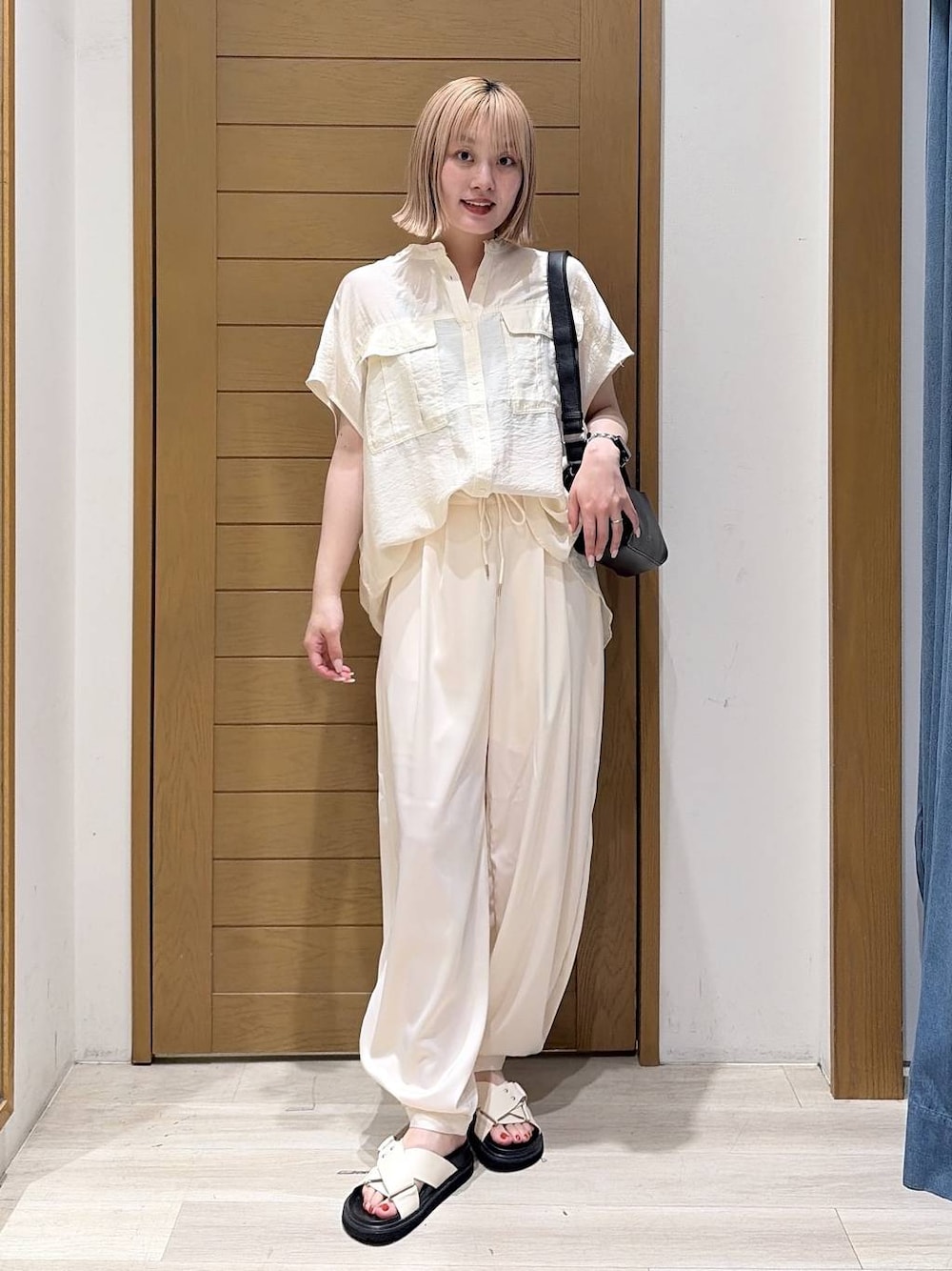 ベージュ系のその他パンツ、ホワイト系のシャツ/ブラウス、ホワイト系のサンダルを着用したレディースの夏コーディネートの1枚目の写真