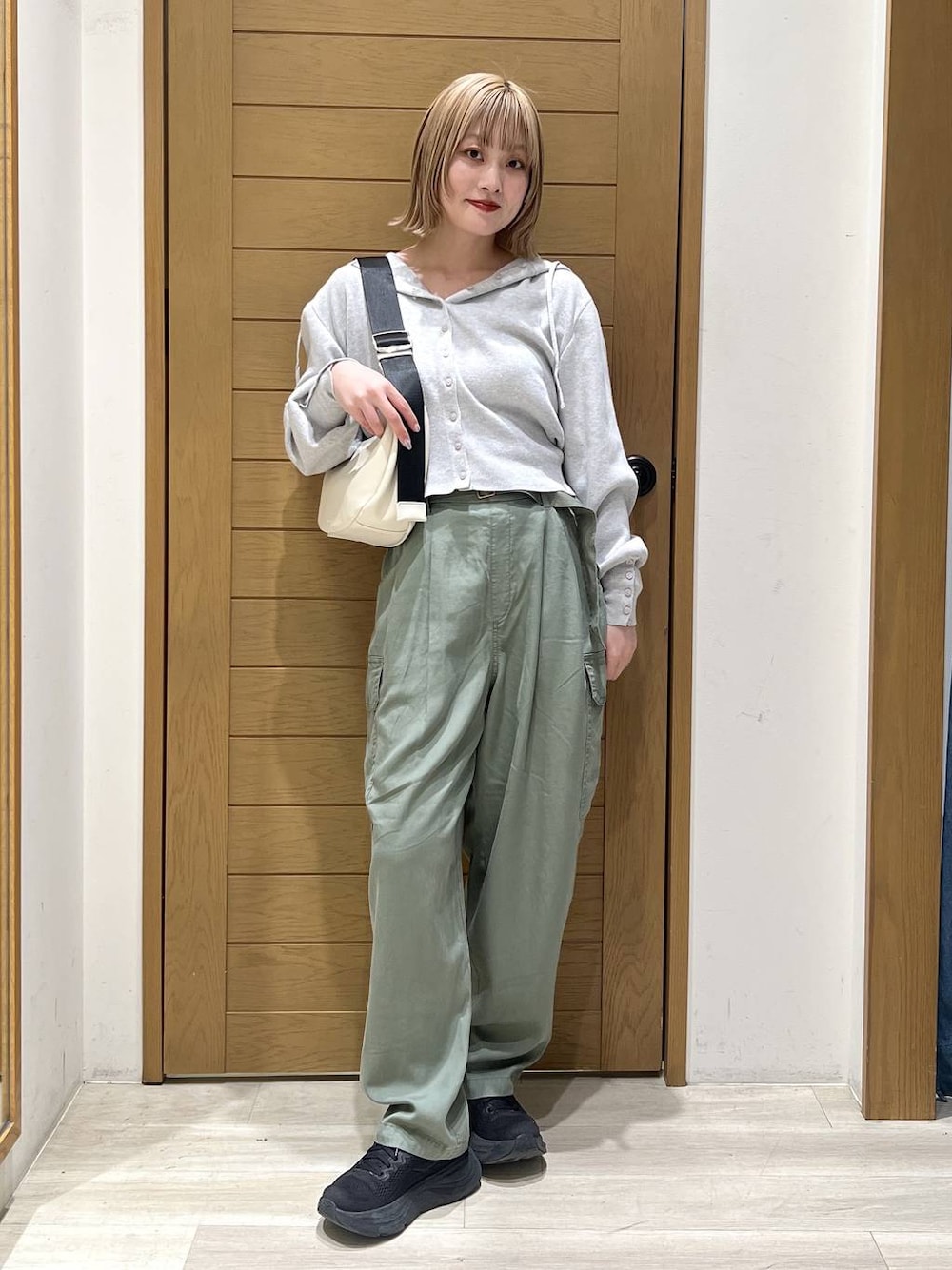 グリーン系のカーゴパンツ、ホワイト系のショルダーバッグ、グレー系のパーカーを着用したレディースの春コーディネートの1枚目の写真