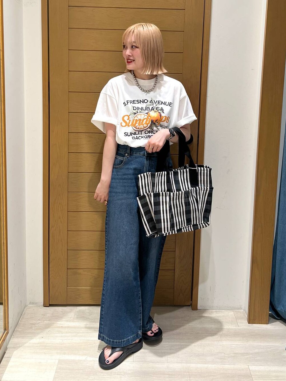 ブルー系のデニムパンツ、オレンジ系のTシャツ/カットソー、ブラック系のサンダルを着用したレディースの夏コーディネートの1枚目の写真