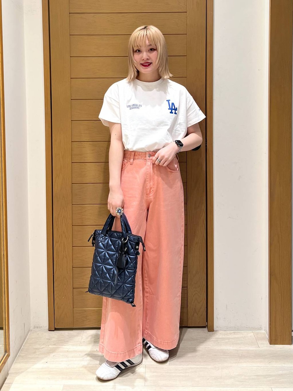 ピンク系のデニムパンツ、ブルー系のハンドバッグ、ホワイト系のTシャツ/カットソーを着用したレディースの春コーディネートの1枚目の写真