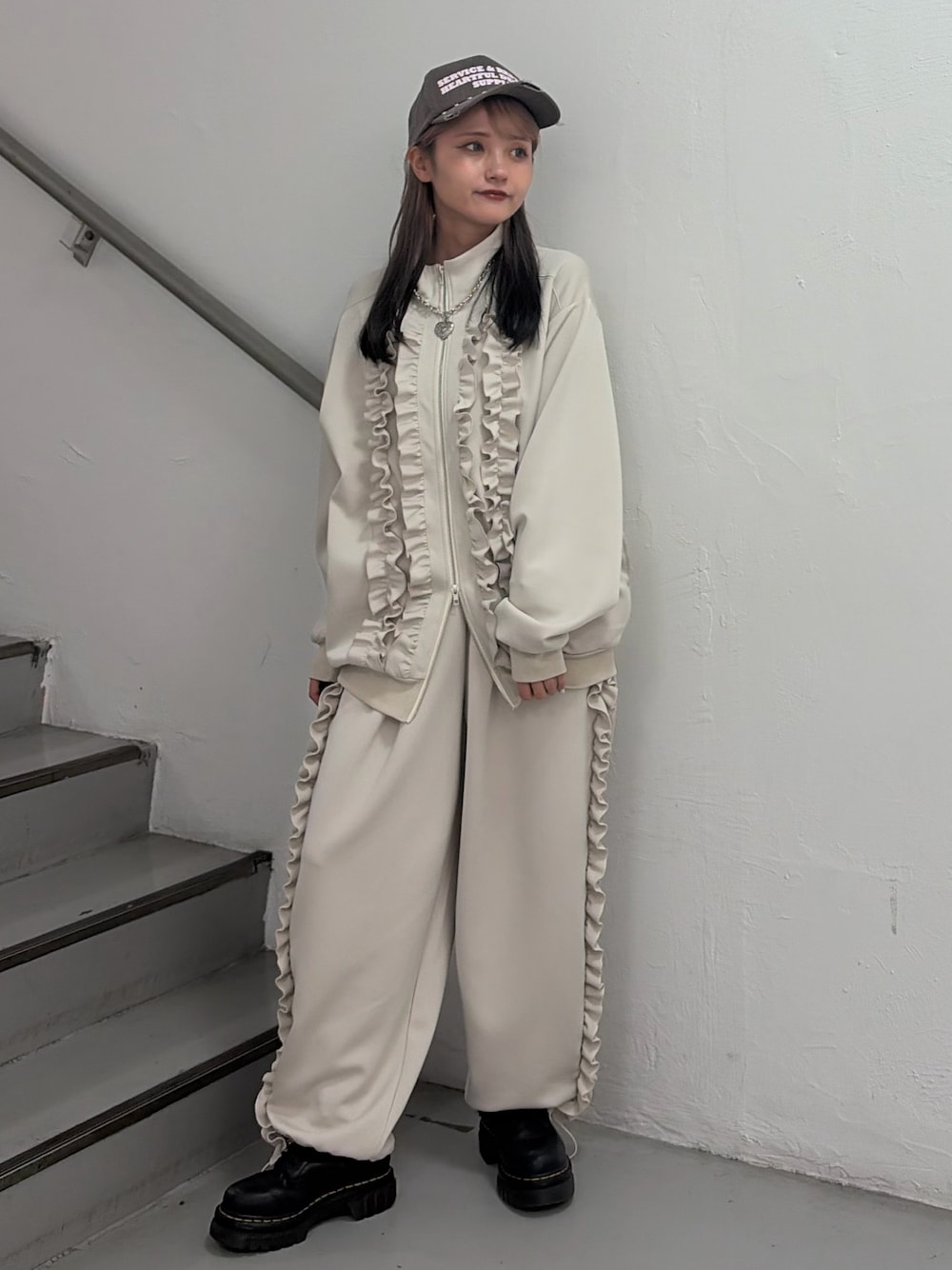 ホワイト系のジャージ、ホワイト系のその他パンツ、ブラウン系のキャップを着用したレディースの冬コーディネートの1枚目の写真