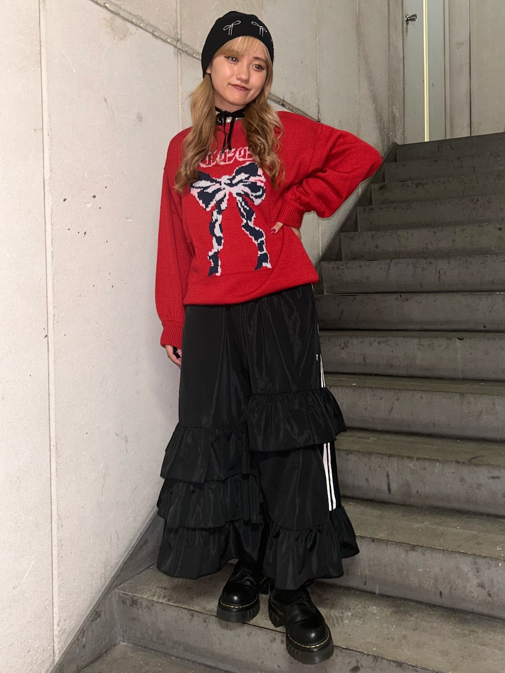 レッド系のニット/セーター、ブラック系のスカート、ブラック系のチョーカーを着用したレディースの秋コーディネートの1枚目の写真