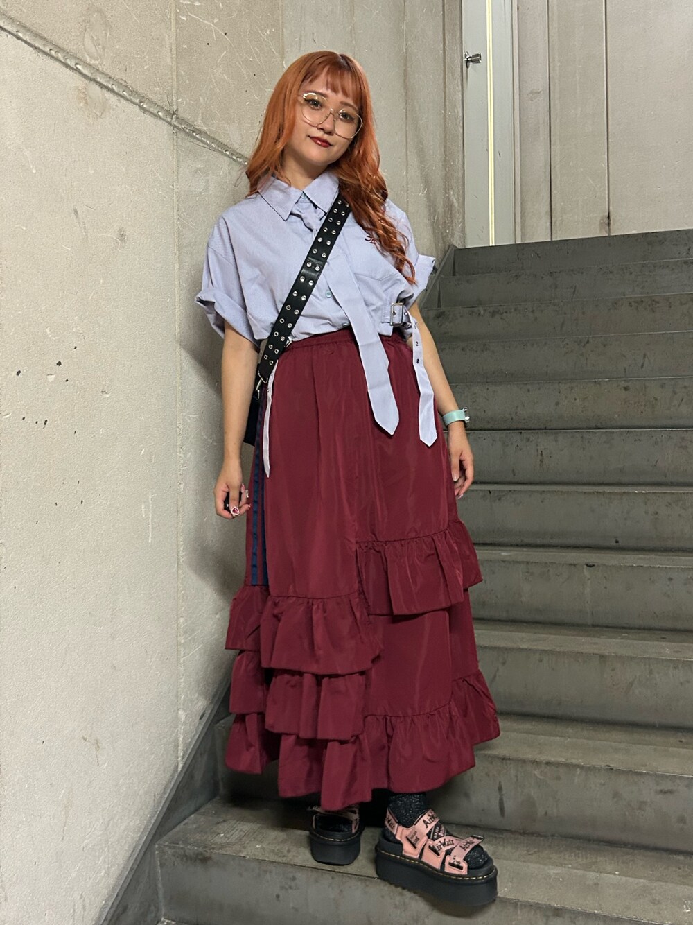 パープル系のシャツ/ブラウス、レッド系のスカート、ブラック系のショルダーバッグを着用したレディースの夏コーディネートの1枚目の写真