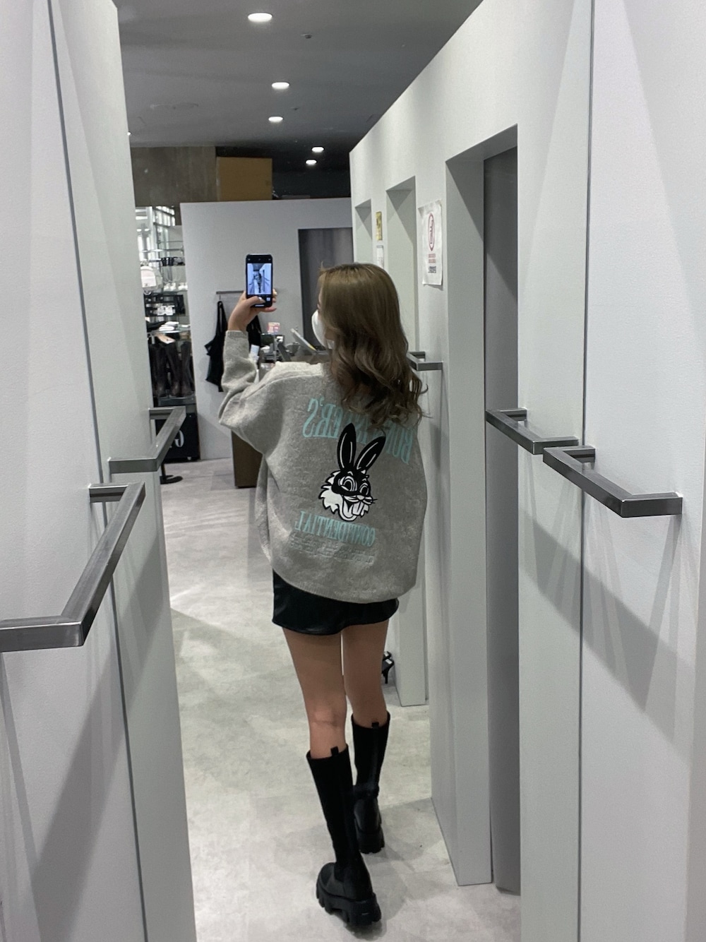 グレー系のニット/セーター、ブラック系のスカート、ブラック系のブーツを着用したレディースの冬コーディネートの1枚目の写真