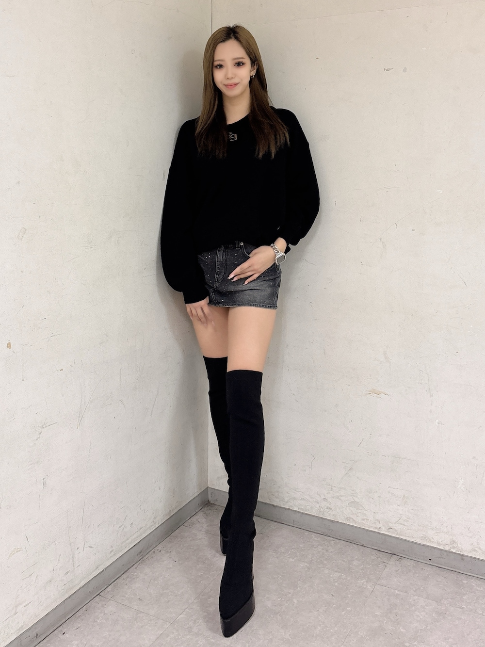 ブラック系のニット/セーター、ブラック系のデニムスカート、ブラック系のブーツを着用したレディースの冬コーディネートの1枚目の写真