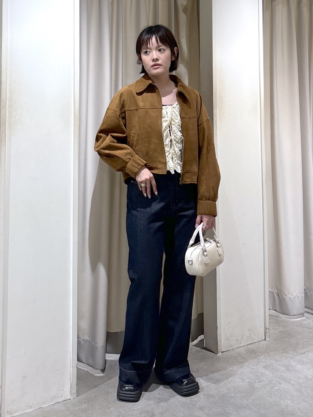 ブラウン系のブルゾン、ホワイト系のニット/セーター、ブルー系のデニムパンツを着用したレディースの秋コーディネートの1枚目の写真